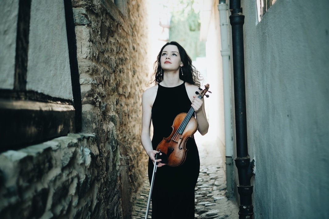 Mairéad Hickey with violin and bow in a narrow alley